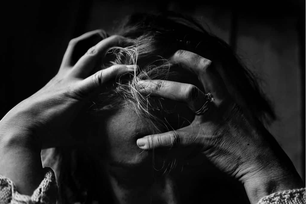 A woman driving her fingers into her head struggling with going cold turkey