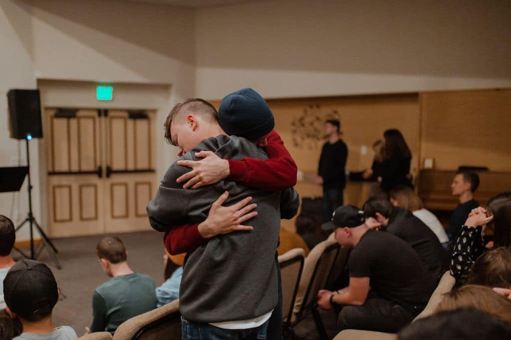 two men embracing in a drug support group