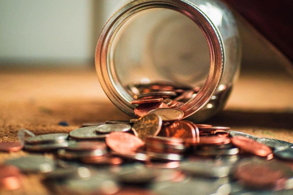 A jar on its side with copper coins spilling out of it - How Much Does Rehab Cost - Which Rehab