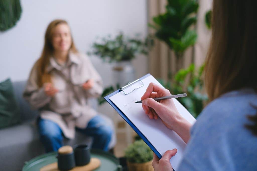 A woman in a rehab therapy session in a room with lush green plants | Which Rehab