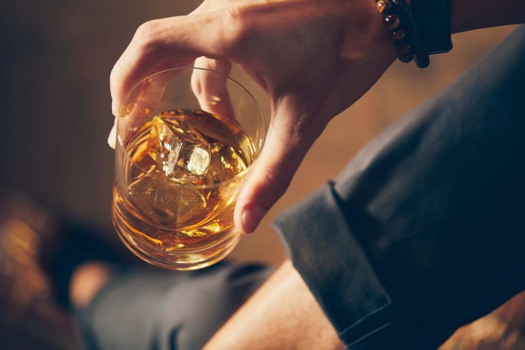 high angle closeup shot male holding glass whiskey | Which Rehab